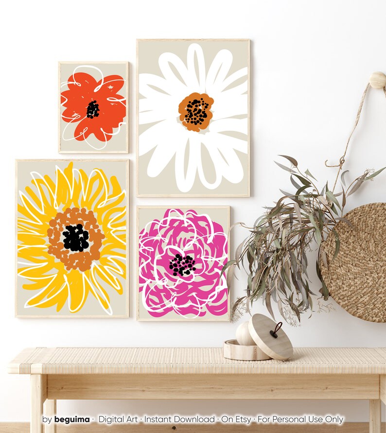 May include: Four framed floral art prints with abstract flower designs in red, white, yellow, and pink. The prints are displayed on a light beige wall. The bottom of the image shows a wooden bench with a woven top.