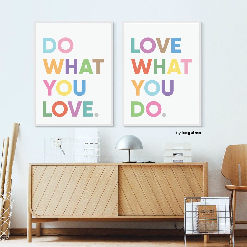 May include: Two framed art prints with the phrases "DO WHAT YOU LOVE" and "LOVE WHAT YOU DO" in colorful block letters. The prints are displayed above a wooden cabinet with a silver lamp and a wire magazine rack.