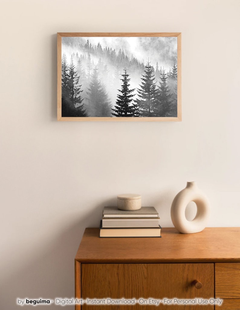 May include: A black and white digital art print of a misty forest with tall pine trees. The print is framed in a light wood frame.