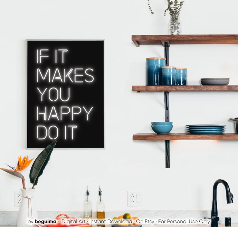 May include: A framed black and white art print with the text "IF IT MAKES YOU HAPPY DO IT". The print is displayed in a modern kitchen setting, alongside wooden shelves with blue ceramic canisters and bowls. A vase with a bird of paradise flower is in the foreground.