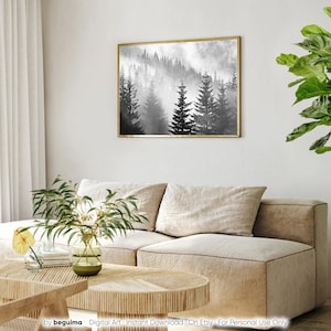 May include: A black and white digital art print of a foggy forest with tall pine trees. The print is framed in a gold frame and hanging on a white wall.