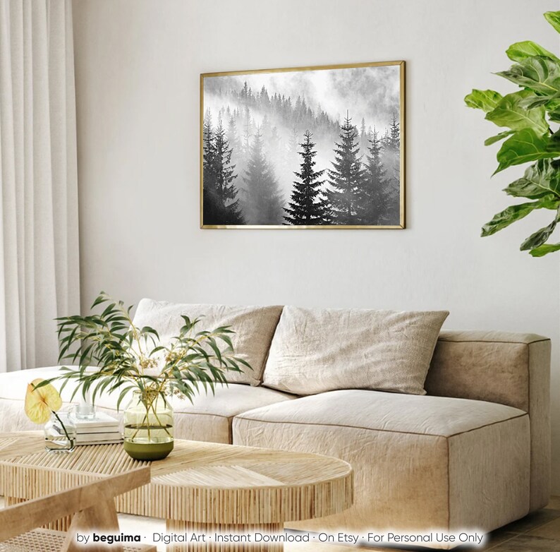 May include: A black and white digital art print of a foggy forest with tall pine trees. The print is framed in a gold frame and hanging on a white wall.