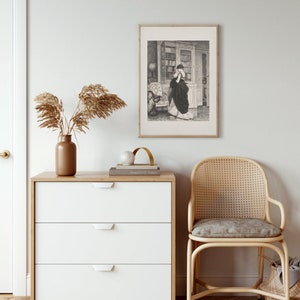 Peut inclure: Une impression encadr&eacute;e en noir et blanc d'une femme en robe longue, debout dans une biblioth&egrave;que. L'impression est suspendue au-dessus d'une commode blanche &agrave; trois tiroirs avec un dessus en bois. Un vase marron avec des plantes s&eacute;ch&eacute;es et une chaise en osier sont &eacute;galement dans l'image.
