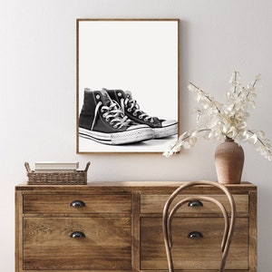 Puede incluir: Impresi&oacute;n enmarcada de zapatillas altas en blanco y negro. Las zapatillas tienen cordones y suelas blancas, con un dise&ntilde;o cl&aacute;sico. La obra de arte se exhibe en una pared blanca sobre una c&oacute;moda de madera. Descarga de arte digital.