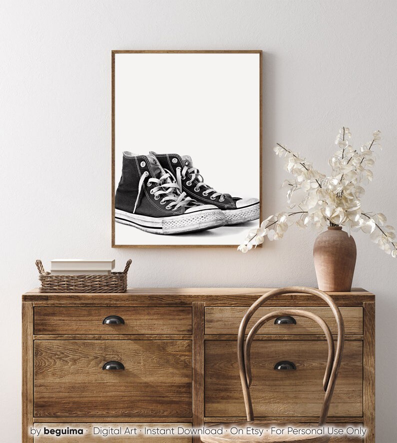 Puede incluir: Impresi&oacute;n enmarcada de zapatillas altas en blanco y negro. Las zapatillas tienen cordones y suelas blancas, con un dise&ntilde;o cl&aacute;sico. La obra de arte se exhibe en una pared blanca sobre una c&oacute;moda de madera. Descarga de arte digital.