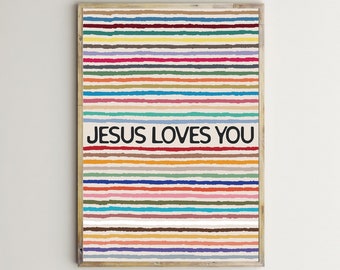 May include: A colorful striped poster with the text "JESUS LOVES YOU" in black lettering. The poster has a wooden frame and a white background.