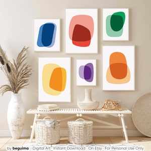 May include: Set of six abstract digital art prints featuring overlapping shapes in various colors, including blue, red, green, yellow, orange, and purple. The prints are displayed on a white wall above a white bench.