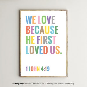 May include: A colorful printable wall art design with the text "WE LOVE BECAUSE HE FIRST LOVED US." and the scripture reference "1 JOHN 4:19".