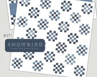 May include: A quilt pattern called "Snowbird" from the Thimble Blossoms collection by Camille Roskelley. The pattern is a classic strip pieced quilt with a blue and white checkered design. The quilt is 74 inches in size.