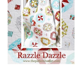 May include: A white quilt with a red, white, and blue pattern. The quilt is folded and displayed on a white chair. The quilt is called "Razzle Dazzle" and is available from The Pattern Basket.