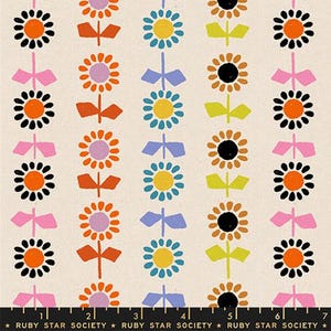 May include: A cream-colored fabric with a repeating pattern of stylized flowers and bows in orange, black, pink, yellow, and blue. The flowers have black centers and orange or yellow petals. The bows are pink or blue.