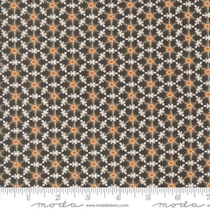 May include: A fabric with a repeating floral pattern. The flowers are white with orange centers, set against a dark brown background. The fabric has a ruler along the bottom edge.