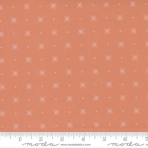 May include: A peach-colored fabric with a white cross-stitch pattern. The fabric is textured and has a subtle sheen.