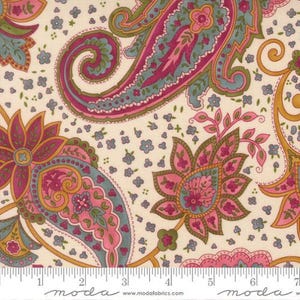 May include: Paisley fabric with a cream background. The fabric features large paisley designs in pink, teal, and green, with smaller blue floral accents. Gold-colored stems and outlines add detail to the design. The fabric is marked with a ruler.