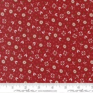 May include: A deep red fabric featuring a repeating pattern of small white and light pink flowers with olive green centers, accompanied by tiny white dots and stems. A white ruler is visible at the bottom, measuring up to 7 inches.