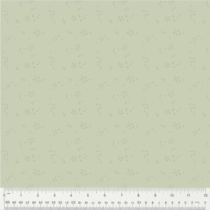 May include: A light green fabric with a repeating pattern of small, four-pointed star shapes. The stars are a darker shade of green than the background. A ruler is at the bottom, showing inches and centimeters.