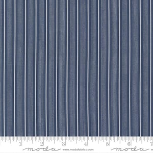 May include: Close-up of a fabric with a navy blue background and vertical white stripes. The fabric has a ruler along the bottom edge, with the word "moda" printed on it.