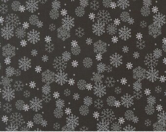 May include: A dark charcoal gray fabric featuring a repeating pattern of white and light gray snowflakes in various sizes and intricate geometric designs, with a white ruler visible at the bottom edge showing measurements in inches.
