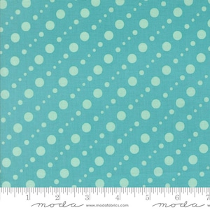 May include: A turquoise fabric with a repeating pattern of white polka dots in diagonal rows. The fabric has a textured appearance and a ruler is visible along the bottom edge. The fabric is from Moda Fabrics.