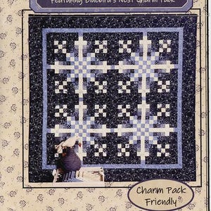 May include: A quilt kit titled "Icy Blue" featuring a blue and white patchwork design. The kit includes a "Bluebird's Nest Charm Pack" and is designed by Lynne Hagmeier of Kansas Troubles Quilters. The quilt has a floral border.