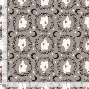 May include: A taupe fabric featuring a repeating pattern of white ghosts holding orange pumpkins, enclosed in black leafy wreaths, interspersed with black crescent moons and white stars, with a ruler showing 11 inches along the edge.