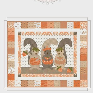 May include: A patchwork quilt featuring three cartoon squirrels with acorns and hats. The quilt has a white border and a patterned orange and tan background. The text "My Squirrelly Friends" is at the bottom.