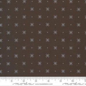 May include: Brown fabric with a white repeating pattern of small crosses. The fabric is measured with a ruler in inches.