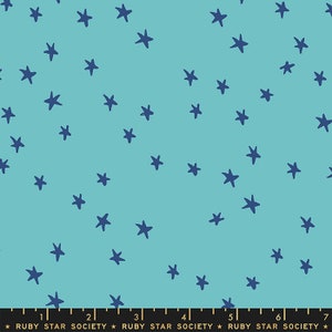 May include: A turquoise blue fabric with a repeating pattern of navy blue stars. The fabric is marked with a ruler in inches and the text "RUBY STAR SOCIETY".