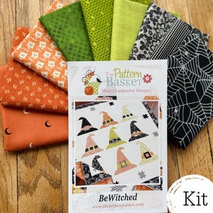 May include: A fabric bundle featuring orange, green, and black patterned cotton squares alongside a quilt pattern booklet titled BeWitched by The Pattern Basket. The fabrics include prints of moons, geometric shapes, spiderwebs, and lace patterns.