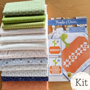 May include: A stack of patterned fabric squares in various colors, including green, white, blue, and orange. A booklet titled "Pumpkin & Denim" is visible, with illustrations of a pumpkin and a plant. The word "Kit" is also visible.
