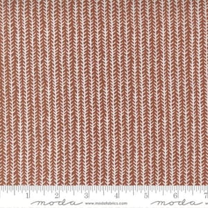 May include: A white fabric with a repeating pattern of brown chevron stripes. The fabric is measured in inches with a ruler at the bottom of the image. The ruler has the word "moda" printed on it.