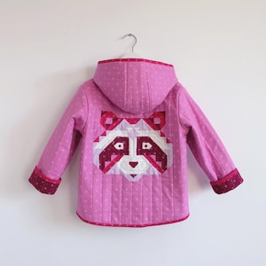 May include: A pink hooded jacket with a raccoon design on the back. The jacket has a quilted pattern with white polka dots and a red trim. The raccoon is made of geometric shapes in shades of red, white, and pink.