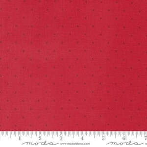 May include: A vibrant red fabric featuring a repeating pattern of small, dark red polka dots. A white ruler is visible at the bottom edge, showing a scale of 7 inches, with the text "moda" and "www.modafabrics.com" printed along the bottom.