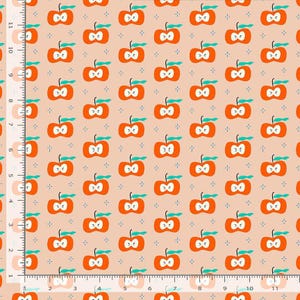 May include: A light peach fabric featuring a repeating pattern of orange apple halves with teal stems and leaves, interspersed with small dark blue four-pointed stars. A white ruler with inch markings is visible along the left and bottom edges.