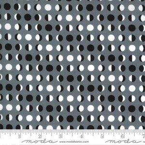 May include: Gray fabric with a repeating pattern of black and white half-circles. The fabric is marked with a ruler in inches and the text "moda" appears twice.