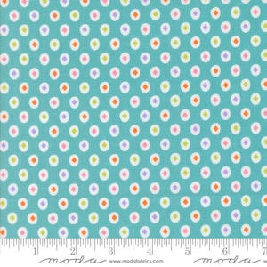 May include: Teal fabric with a repeating pattern of white circles, each containing a small, colorful diamond. The diamonds alternate between orange, pink, purple, and green. The fabric has a ruler along the bottom edge.