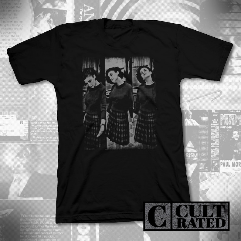 May include: Black t-shirt with a graphic print of three women in black and white. The women are wearing plaid skirts and are standing in a row. The t-shirt has the text "CULT RATED" printed on the bottom.