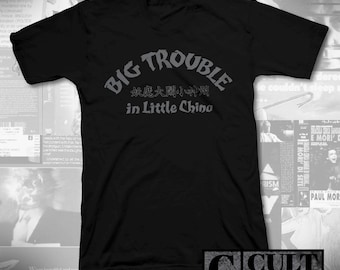 May include: Black V-neck t-shirt featuring the text "BIG TROUBLE in Little China" in grey lettering, with Chinese characters. The shirt also has a "CULT RATED" logo in the bottom right corner.