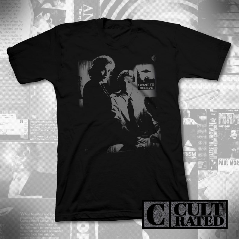 Puede incluir: Camiseta negra con un estampado gr&aacute;fico blanco de dos figuras y un OVNI. El texto "I WANT TO BELIEVE" est&aacute; impreso en el gr&aacute;fico.