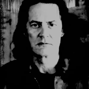 May include: Black and white portrait of a person with long hair. The person has a serious expression and is looking directly at the camera.