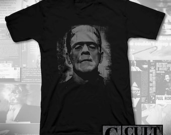 May include: Black V-neck t-shirt with a grayscale image of Frankenstein's monster. The graphic is a portrait of the monster's face. The shirt has the text "CULT RATED" in a rectangular box at the bottom right.