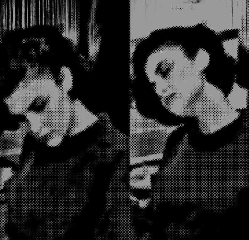 May include: Two women with short dark hair, wearing black shirts, are looking down. The image is in black and white.