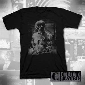 Könnte beinhalten: Schwarzes T-Shirt mit einem grafischen Druck eines Roboters mit einem Beatmungsgerät. Der Roboter ist in Schwarzweiß gehalten. Das T-Shirt trägt ein "Cult Rated"-Label.