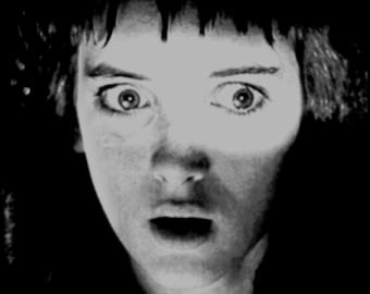 May include: A black and white photo of a person with a surprised expression. The person's eyes are wide open and their mouth is slightly open. The photo is in focus and the person's face is clearly visible.
