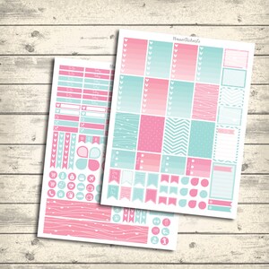 Op de afbeelding: Twee vellen met planner stickers met een roze en blauwe kleurstelling. De stickers bevatten harten, vlaggen, cirkels en andere vormen. De stickers zijn ontworpen voor gebruik in een planner of dagboek.