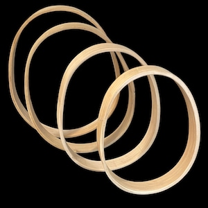May include: Four wooden hoops of varying sizes are stacked on top of each other. The hoops are made of light brown wood and are arranged in a spiral pattern.