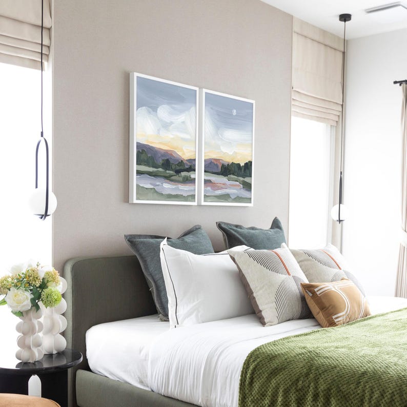 a bedroom with a bed and two paintings on the wall