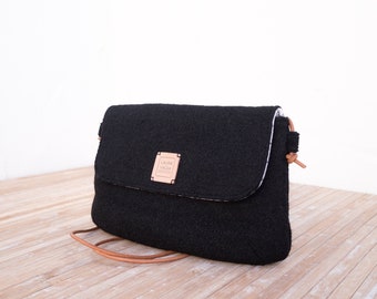 Small black crossbody bag with flap and leather strap.