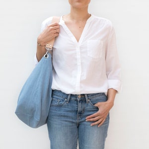 Große und hellblaue Hobo-Tasche. Umhängetasche aus Leinenstoff mit Ledergriff. Hobo für den täglichen Gebrauch bei der Arbeit.