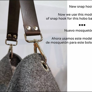 May include: Close-up of a brown leather strap with silver snap hooks attached to a gray felt hobo bag. The text "New snap hook!" and "Now we use this model of snap hook for this hobo bag" is visible in the image.